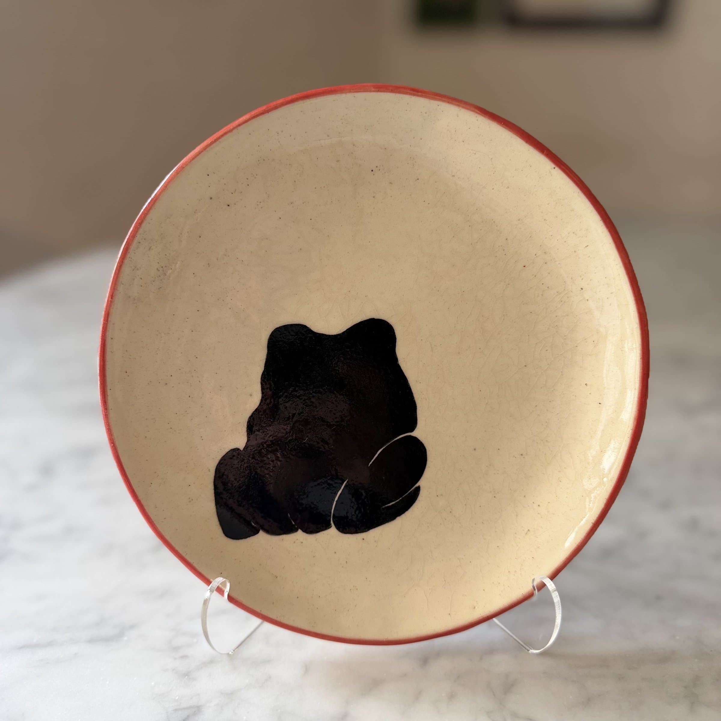 A plate painted with a rear view of a sitting frog.