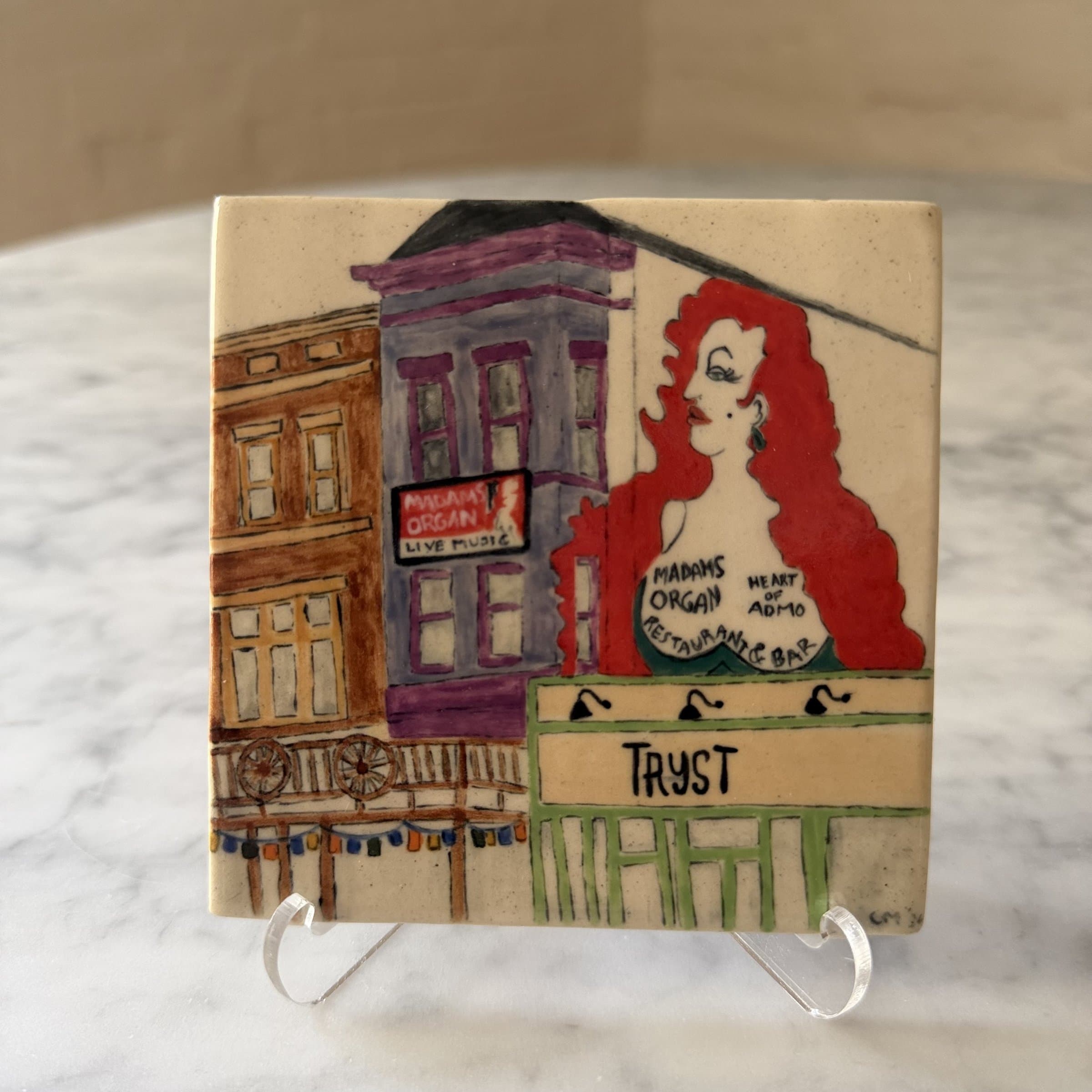 A hand-painted tile of an Adams Morgan street scene — Madam's Organ and Tryst storefronts on 18th.