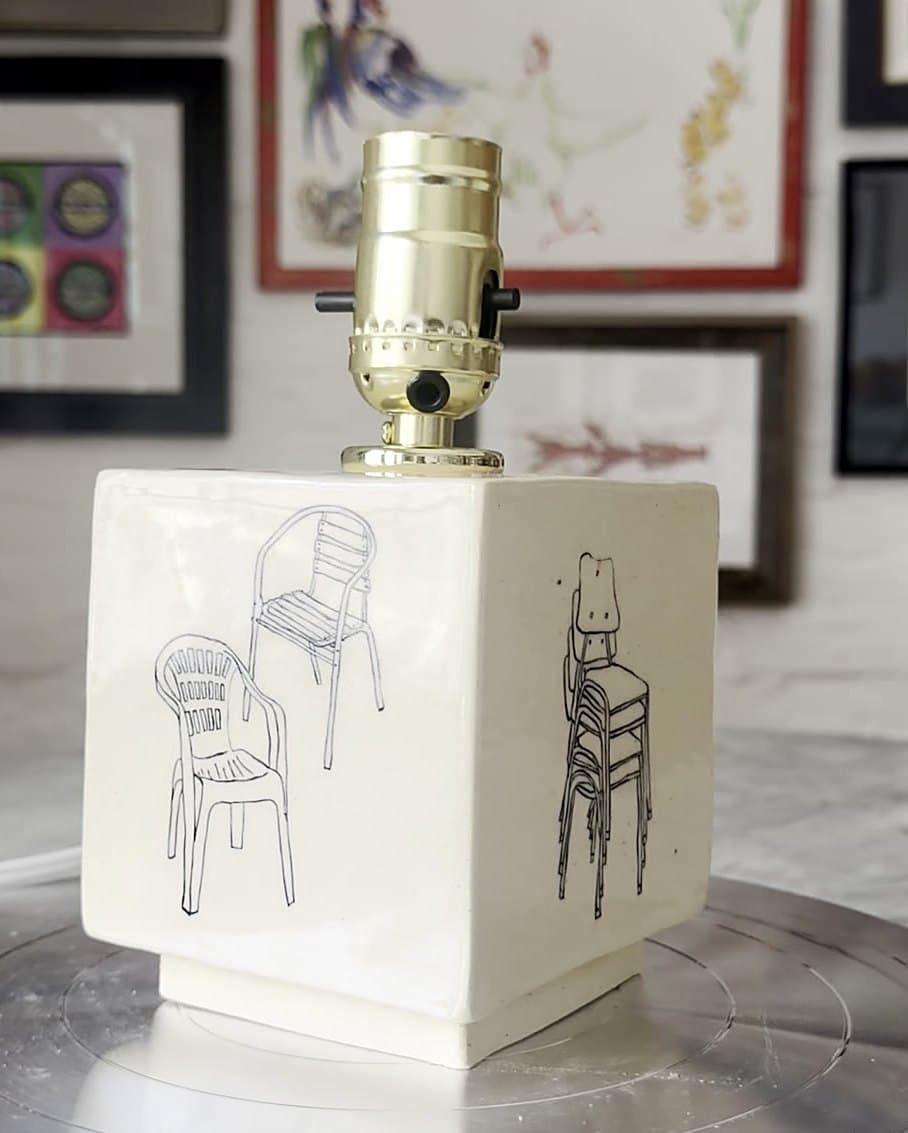 A square ceramic lamp base drawn with patio chairs, stacked chairs and stools, with a brass socket.