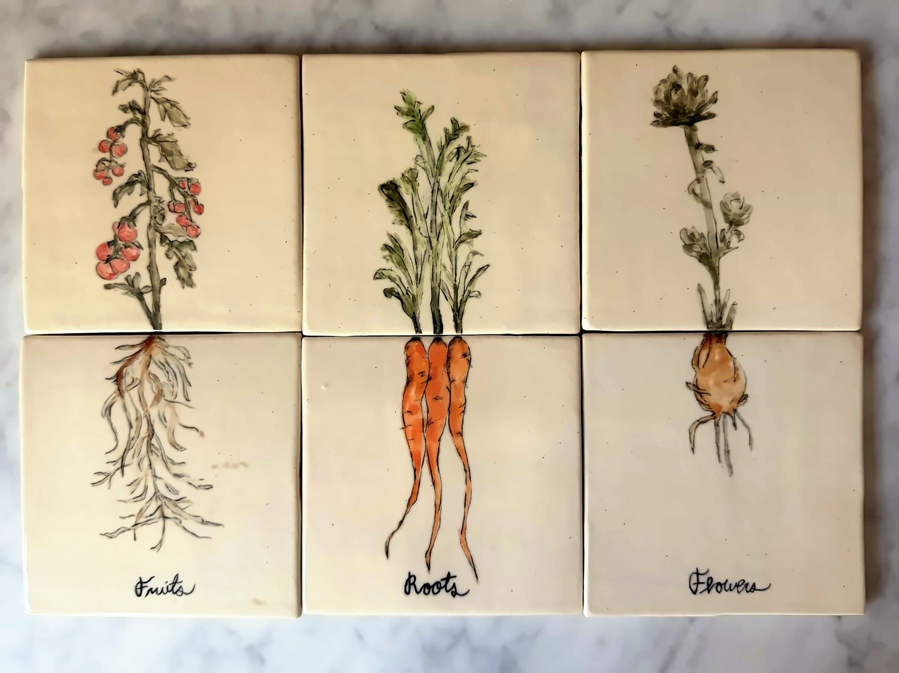 Six painted tiles forming three plants — a tomato vine, carrots and an artichoke — with their roots below, labeled Fruits, Roots and Flowers.